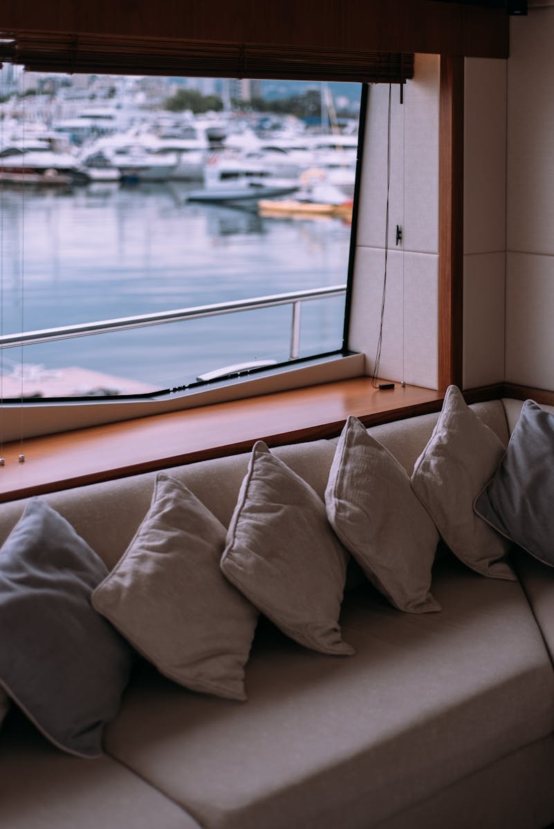 Elegant yacht interior with comfortable seating and harbor view through the window.
